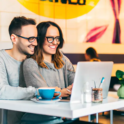 An image showcasing a joyful 25-year-old couple, smiling while sitting in a cozy coffee shop, engrossed in a deep conversation on their laptops