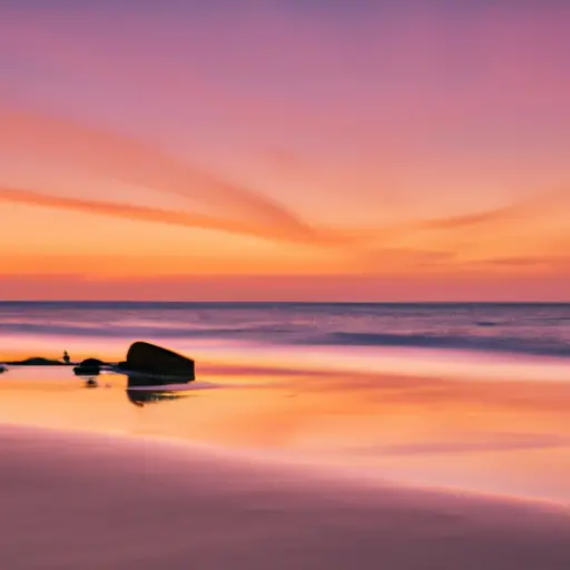 An image showcasing a serene sunrise over a tranquil beach, with gentle waves flowing towards a distant horizon